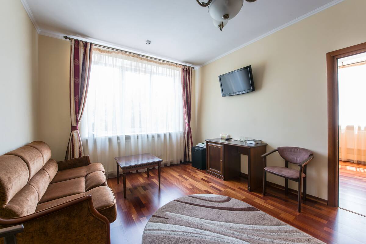A living room with a sofa, a coffee table, a TV mounted on the wall, and a chair.