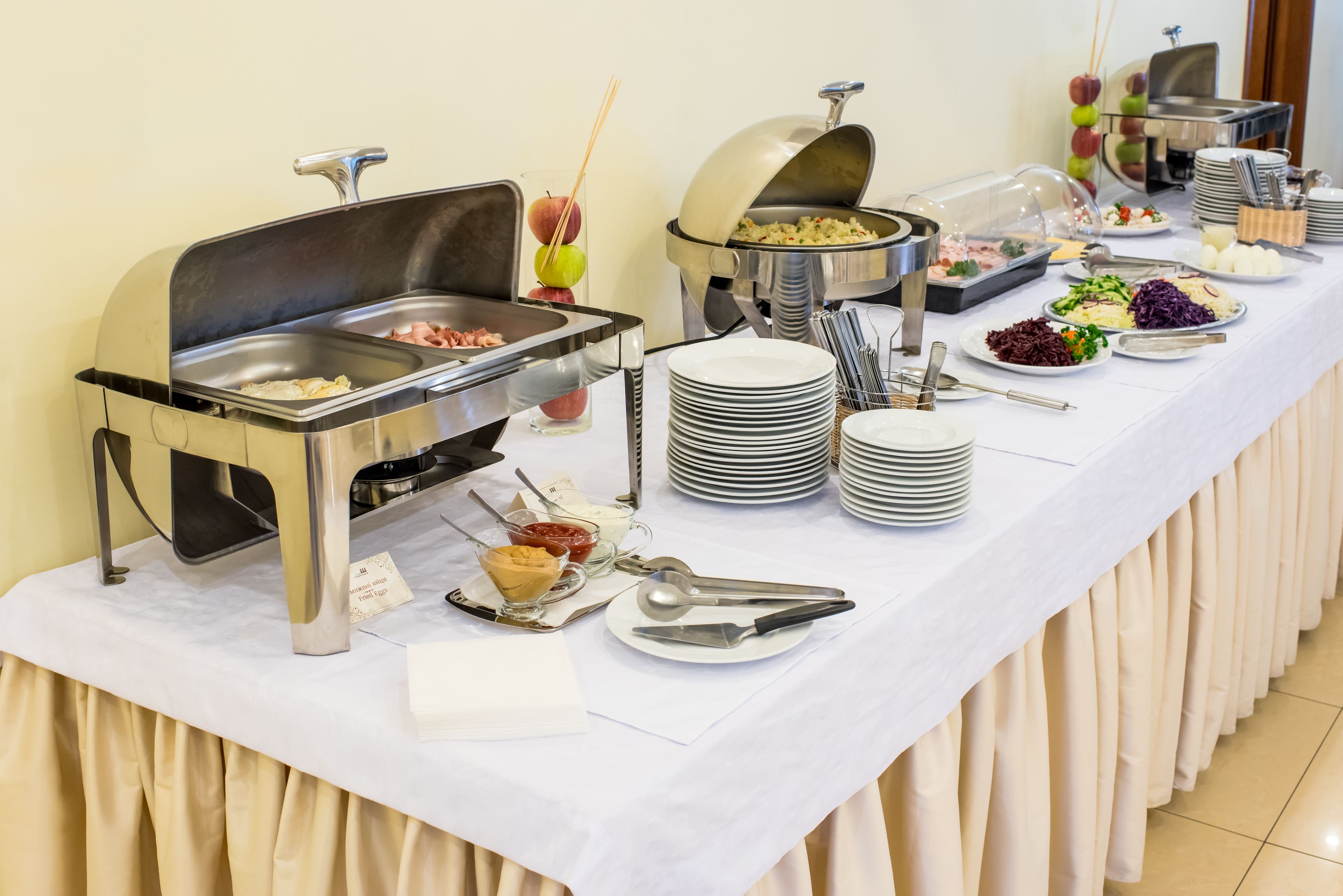 A buffet setup with various food stations, including a grill, salad, and fruit.