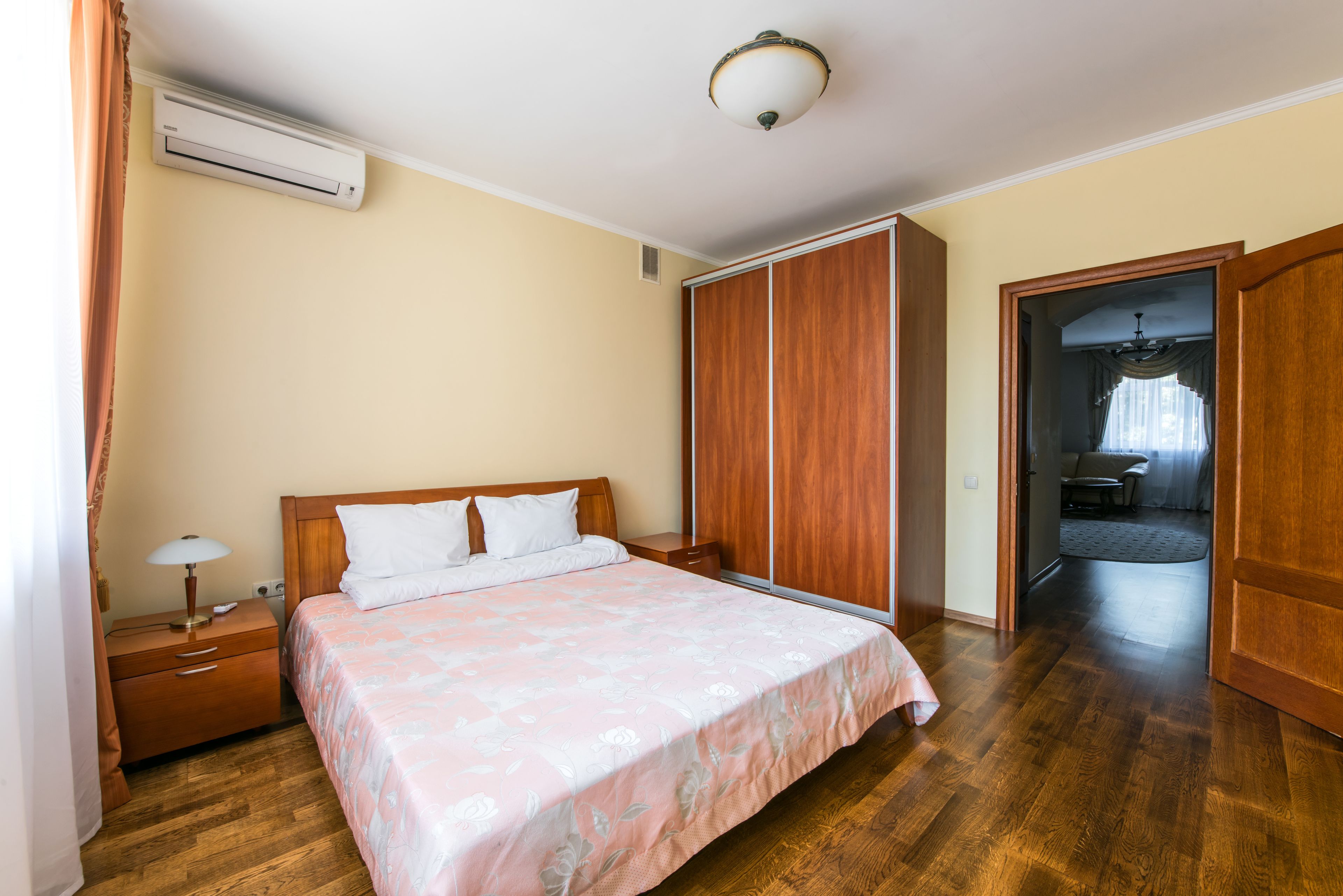 Un dormitorio con una cama de madera, una mesita de noche, un equipo de aire acondicionado y un armario.