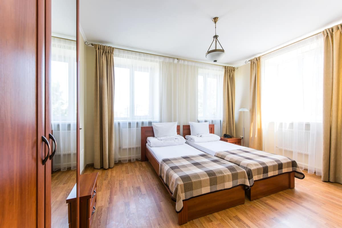 A bedroom with two beds, wooden flooring, a wardrobe, and a ceiling light.