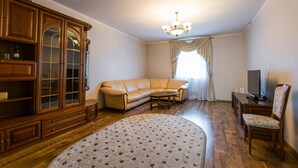 Una sala de estar con un sofá, una mesa de centro, un aparador de madera y un televisor.