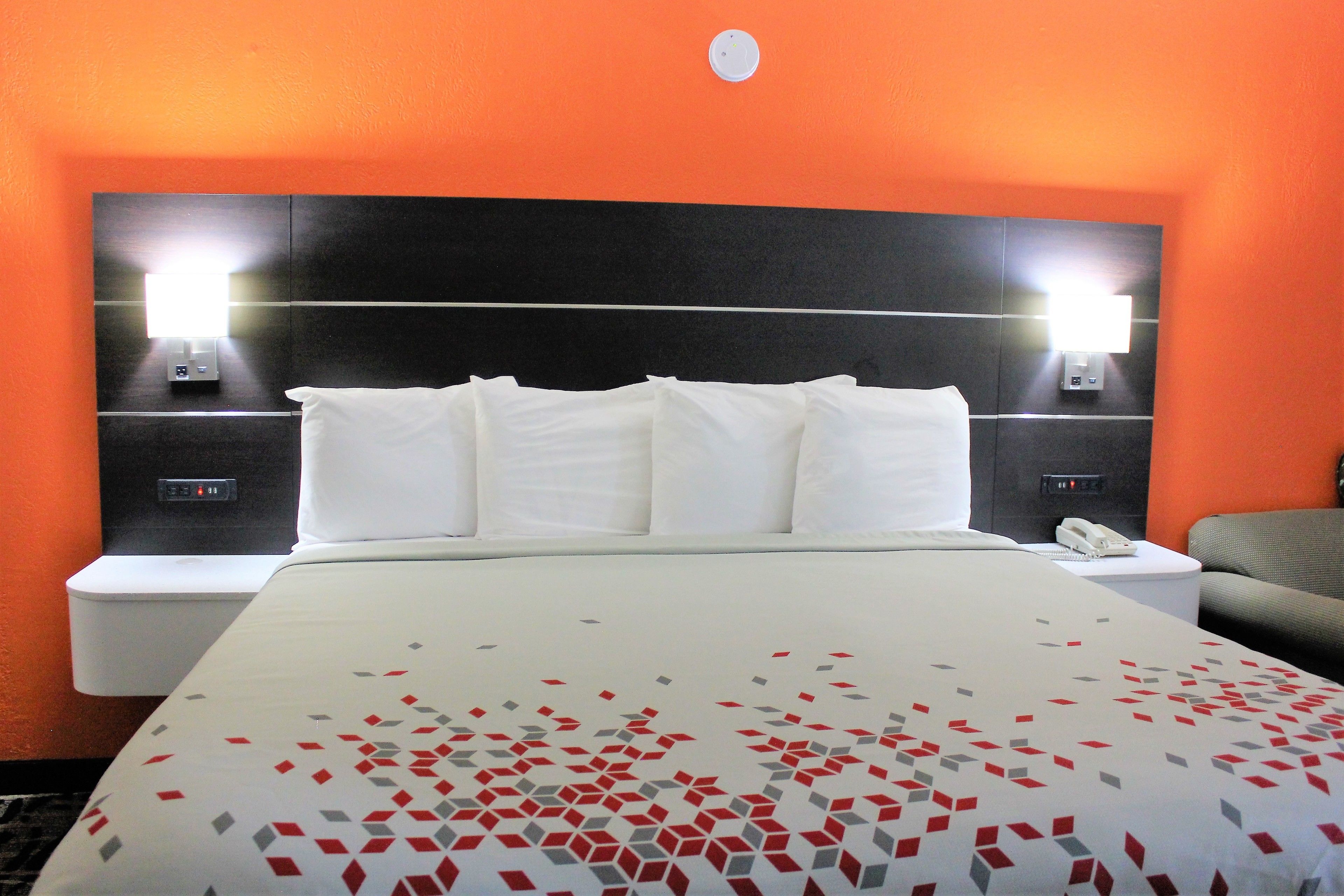 Una habitación de hotel con una cama grande, dos mesitas de noche y una silla.