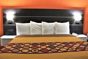 A hotel room with a large bed, two bedside tables, and a headboard with built-in lighting.
