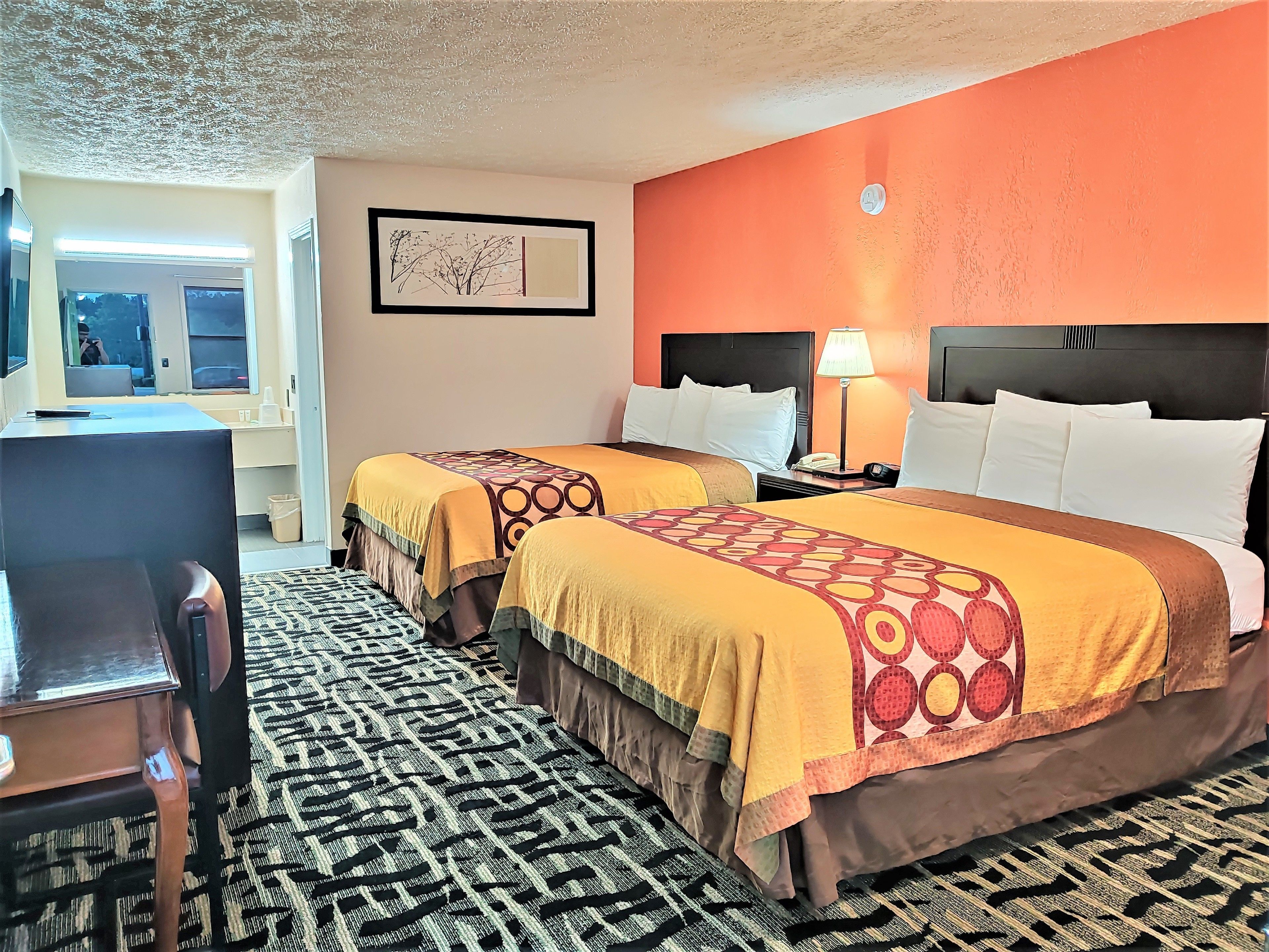 A hotel room with two beds, a desk, and a chair.