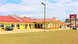Un Travel Inn con techo rojo, exterior amarillo y verde, y un letrero que indica 'Solo vehículos'.