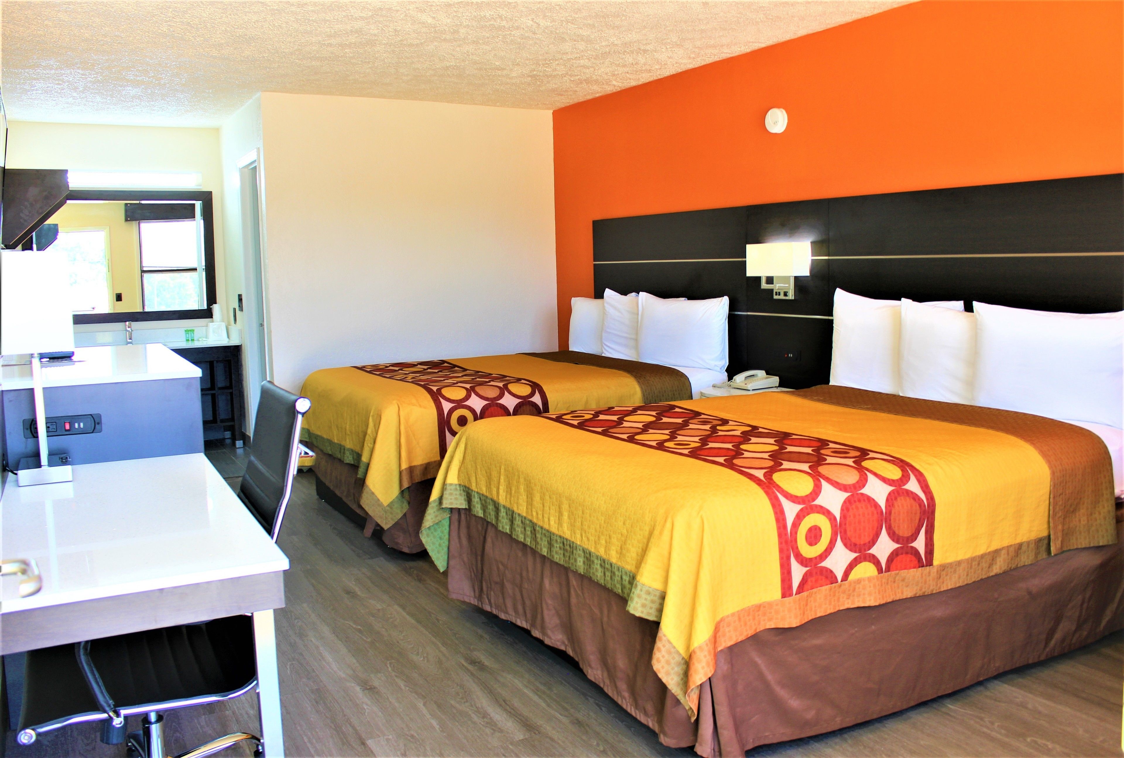 Habitación de hotel con dos camas, un escritorio y un espejo.