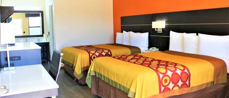 Habitación de hotel con dos camas, un escritorio y un espejo.