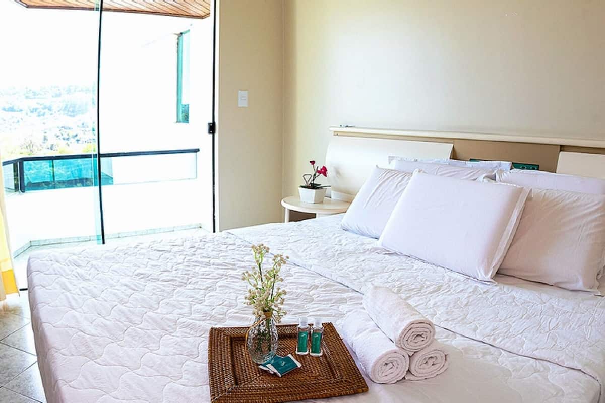 Una habitación de hotel con cama, televisión, escritorio y ventana con cortinas.