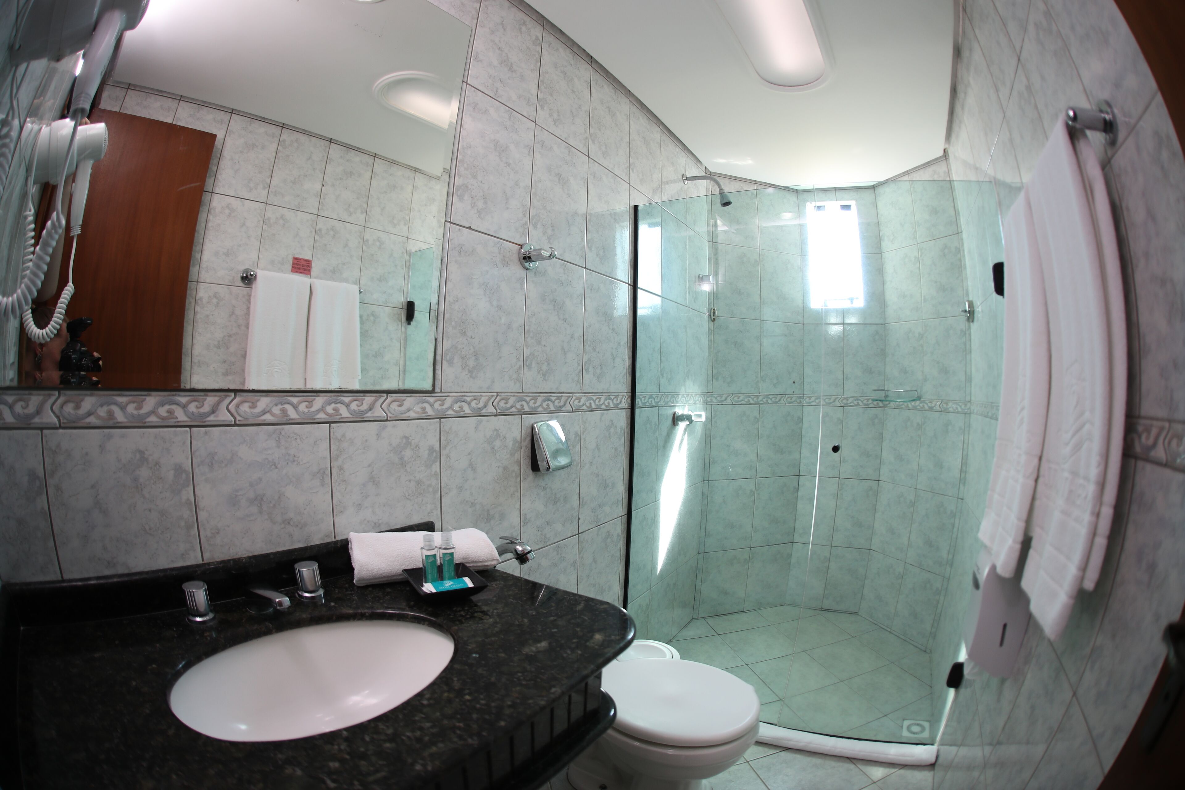 Un baño moderno con cabina de ducha de vidrio, un lavamanos con encimera de mármol y un inodoro.