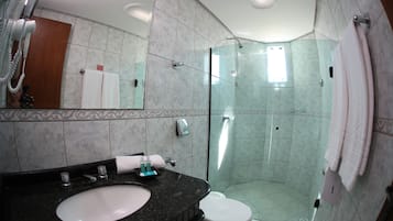 Un baño moderno con cabina de ducha de vidrio, un lavamanos con encimera de mármol y un inodoro.