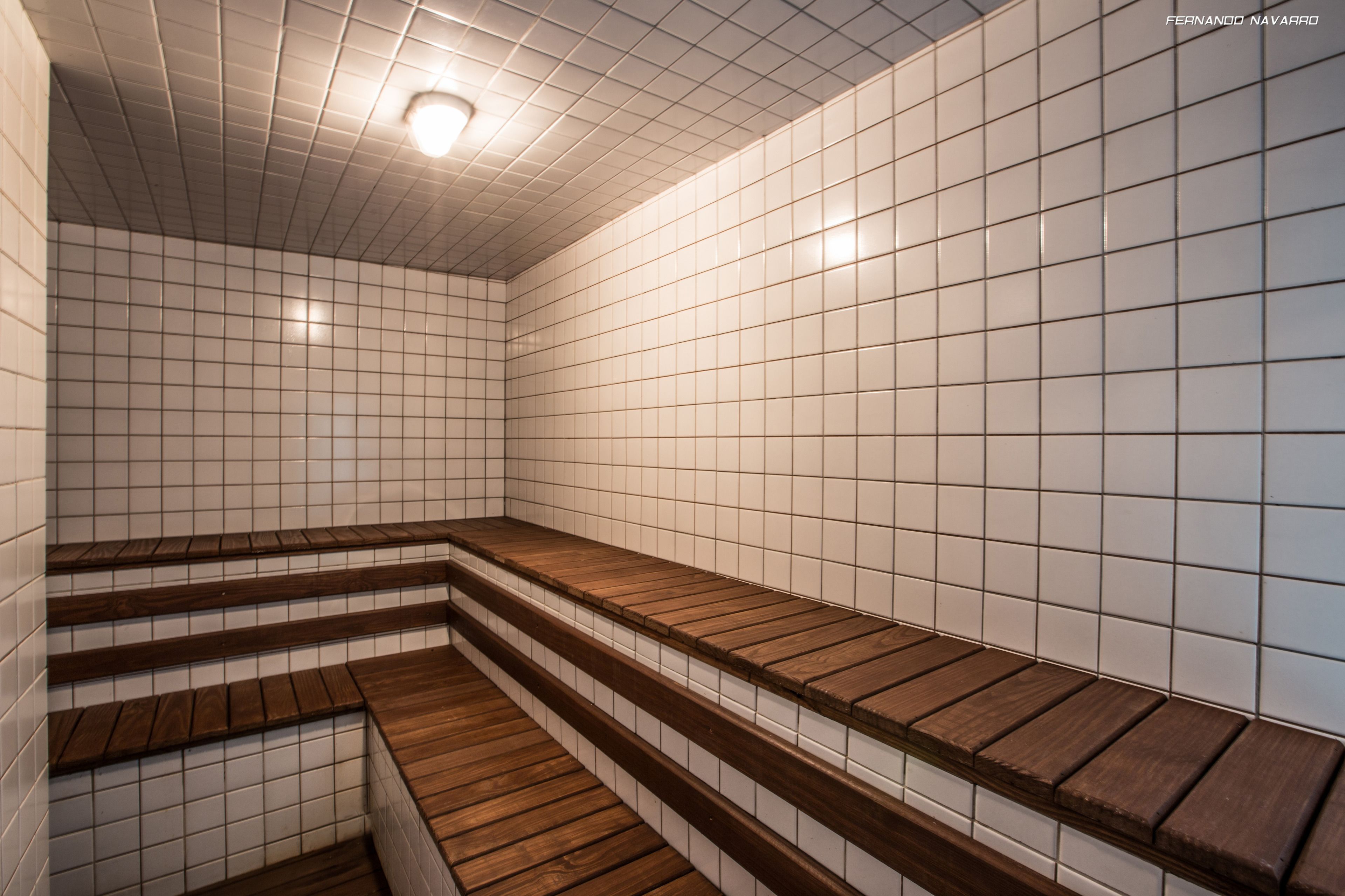 Une salle de bain carrelée avec des marches en bois et un luminaire au plafond.