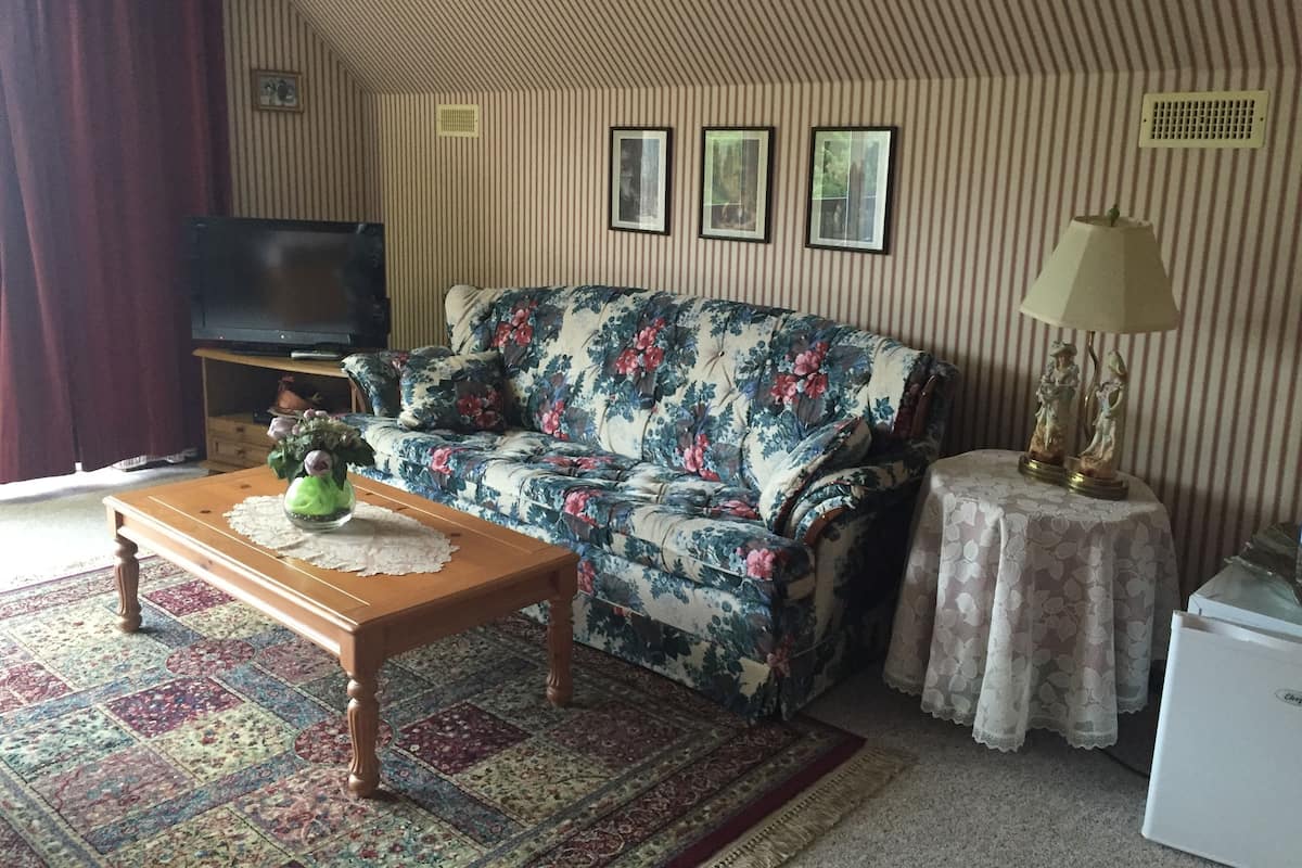 A living room with a floral sofa, a wooden coffee table, a television, and a small table with a lamp.