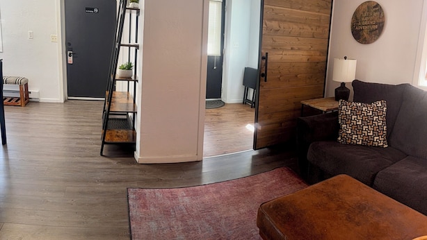 A living room with a dark-colored sofa, a wooden sliding door, a small table with a lamp, and a red rug.