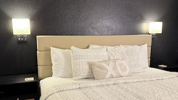 A neatly made bed with patterned bedding, a headboard, and two bedside tables with lamps.