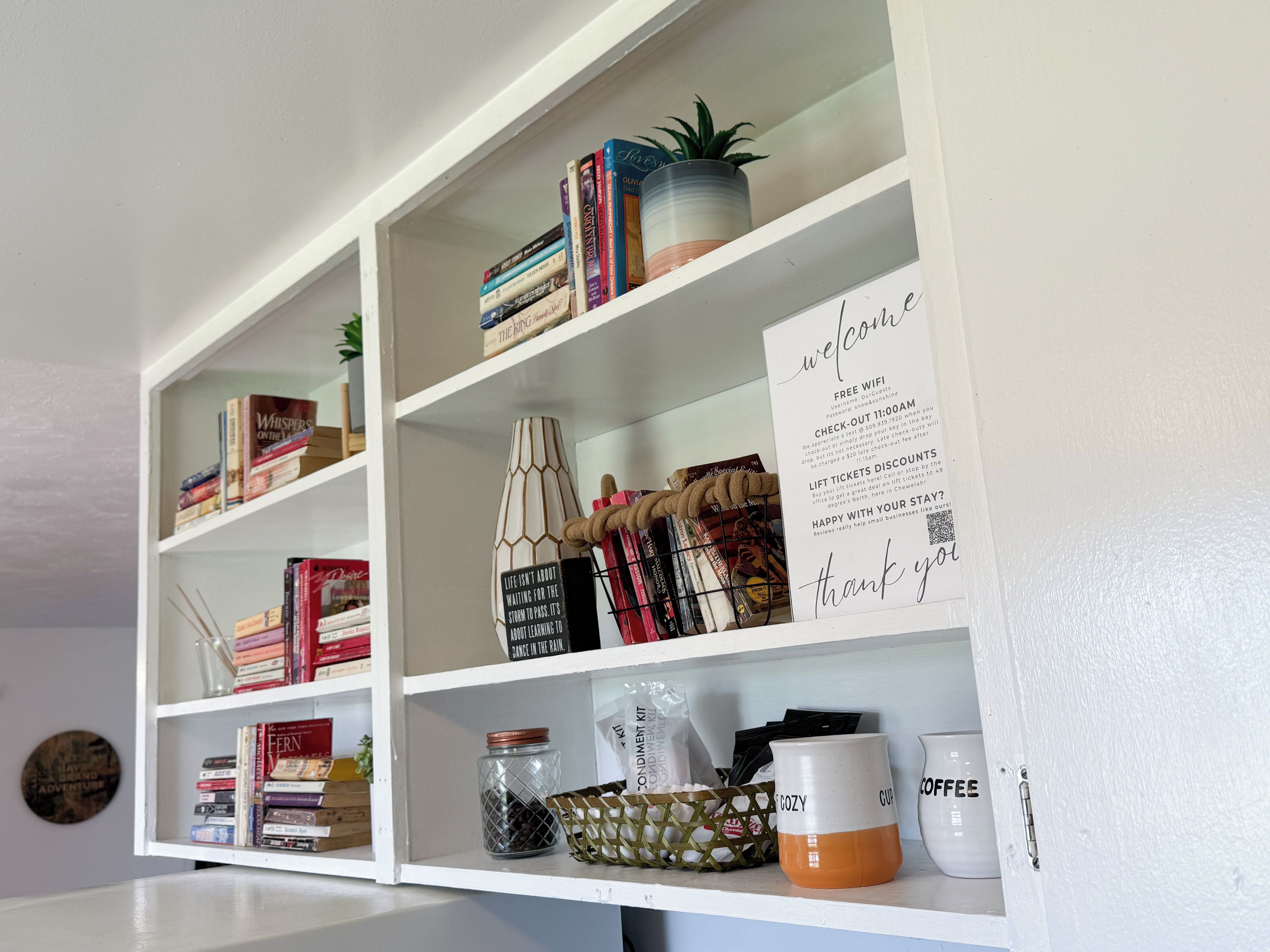 Estante com livros, uma planta em vaso e um aviso oferecendo acesso gratuito à internet e descontos em passes de elevador.