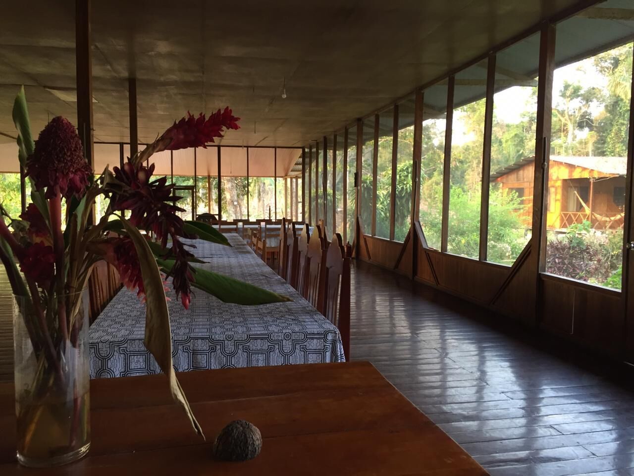 Une pièce spacieuse avec une longue table, des chaises et une grande fenêtre donnant sur un paysage verdoyant.