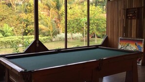 A pool table in a room with large windows overlooking a lush garden. - Monte Amazonico Lodge (Tambopata)