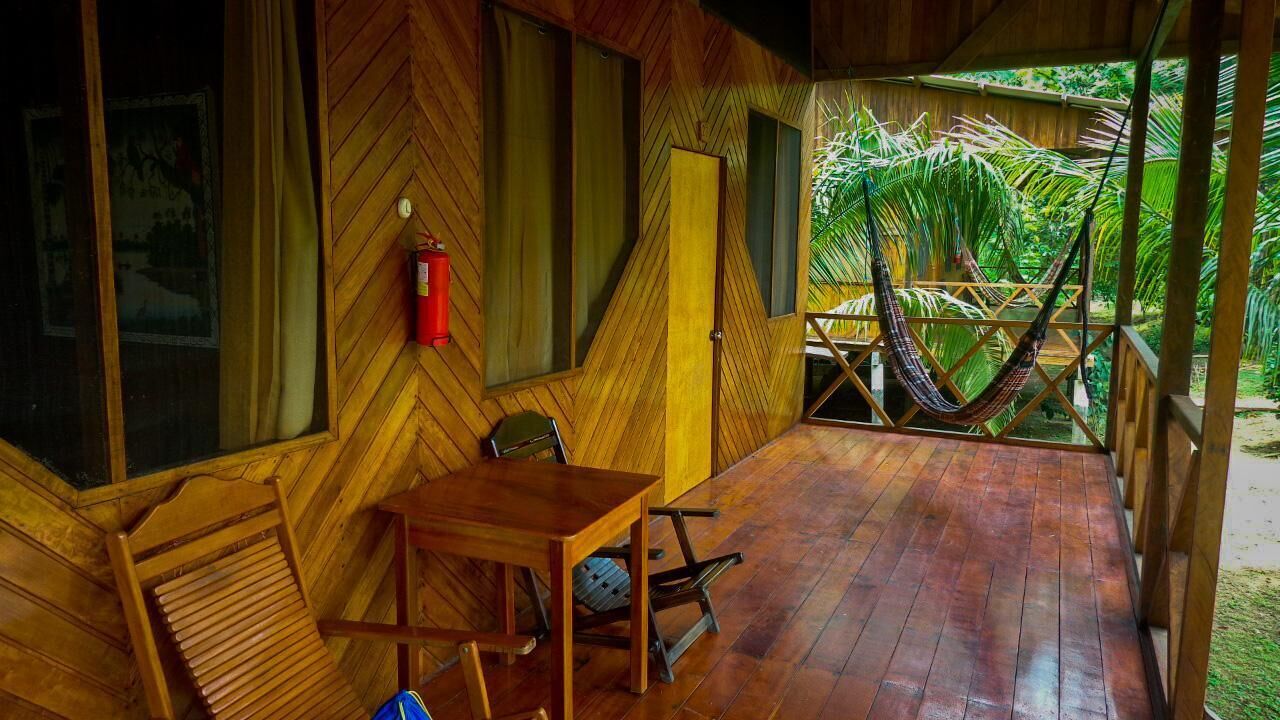 Una habitación de madera con una mesa, sillas, una hamaca y un extintor.