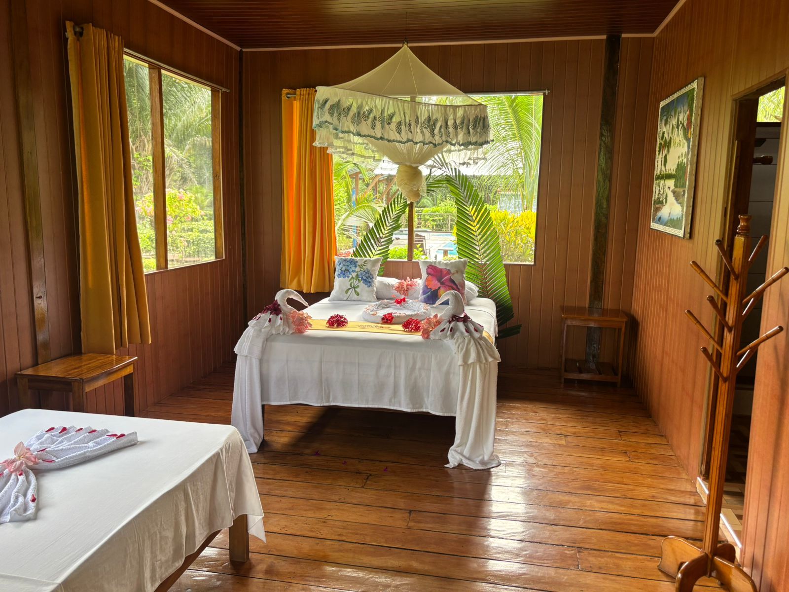 A room with a bed, a bedside table, a hanging chair, and a window with curtains.