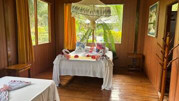 A room with a bed, a bedside table, a hanging chair, and a window with curtains.