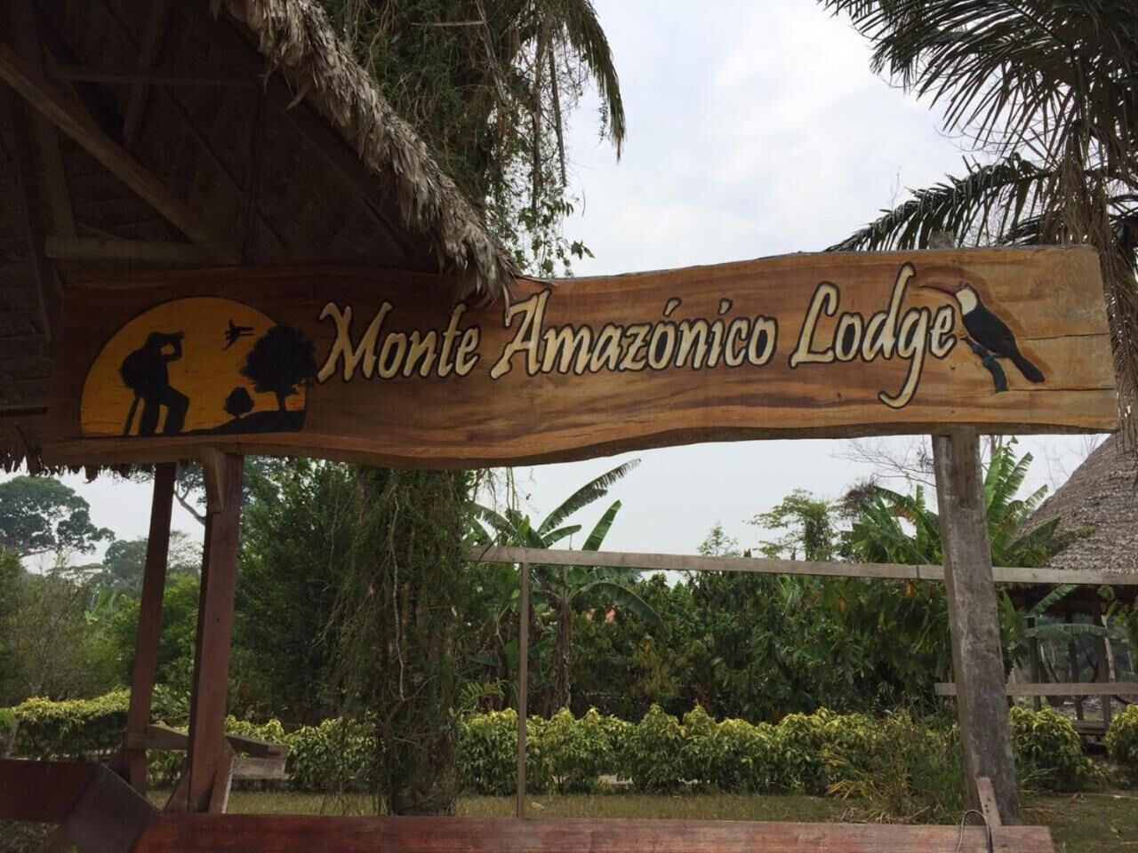 A wooden sign for Monte Amazonas Lodge with a tropical backdrop.