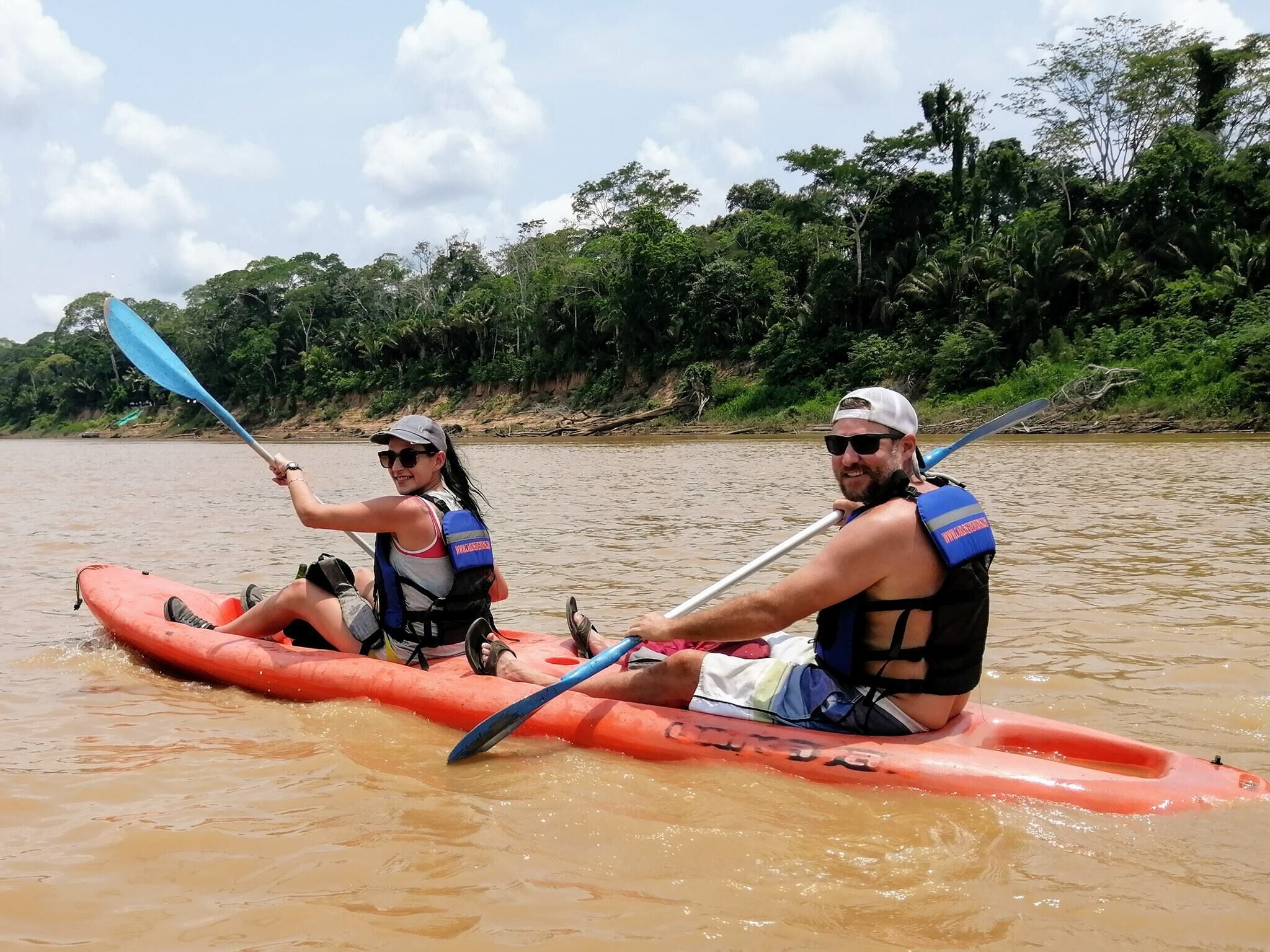Dos personas en kayak en un río rodeado de exuberante vegetación.