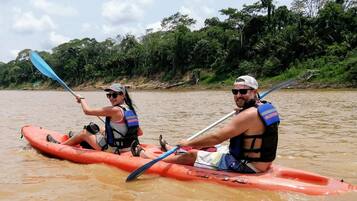 Dos personas en kayak en un río rodeado de exuberante vegetación.