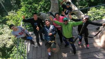 A group of people on a wooden platform with metal railings, surrounded by trees.
