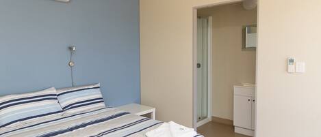 Una camera da letto con un letto, un comodino e un bagno parzialmente visibile attraverso una porta aperta.