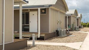 Una hilera de edificios de motel modernos de una sola planta, con unidades individuales, cada una con una puerta numerada, un pequeño porche y unidades de aire acondicionado en el exterior.