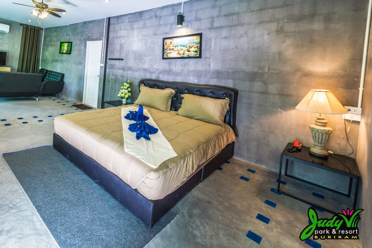 A modern hotel room with a large bed, a desk, a television, and a seating area.