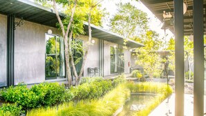Un edificio moderno con amplios ventanales, una zona exterior cubierta y una fuente de agua.