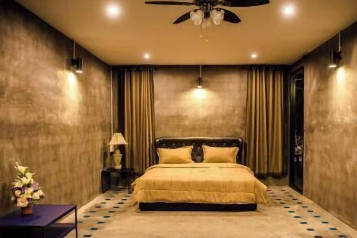 A bedroom with a bed, a ceiling fan, and a nightstand with a lamp.