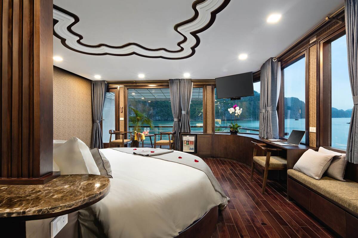 Een hotelkamer met een bed, een bureau, een stoel en uitzicht op een waterpartij.