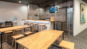 A modern bar area with wooden tables and stools, a water dispenser, and a sign indicating the availability of IPA beer. - Racine Home Kyoto SELF CHECK-IN (Kyoto)