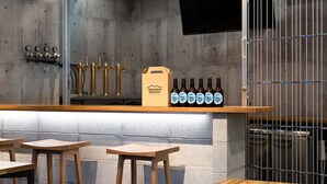 A bar area with stools, a counter displaying bottles, and a wall-mounted clock. - Racine Home Kyoto SELF CHECK-IN (Kyoto)