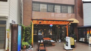 A hotel entrance with a covered outdoor seating area, a signboard, and a potted plant. - Racine Home Kyoto SELF CHECK-IN (Kyoto)