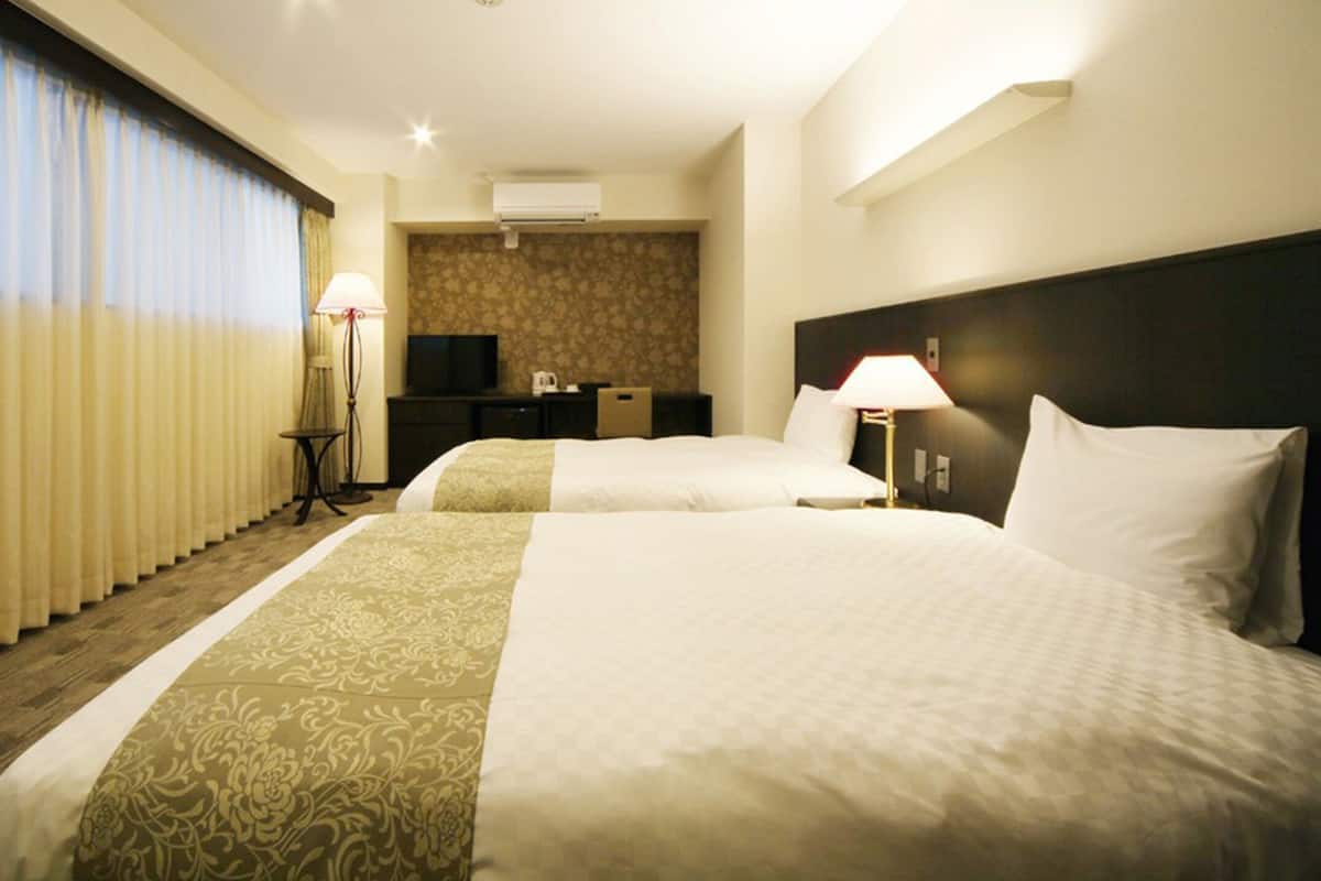 Una habitación de hotel con dos camas, un escritorio, televisor y un minibar.
