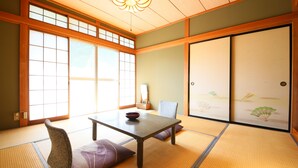 Une pièce de style japonais traditionnel, avec un sol recouvert de tatamis, une table basse, un coussin et des portes coulissantes.