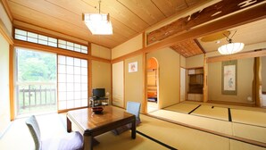 Une pièce de style japonais traditionnel, avec un sol recouvert de tatamis, une table basse, un coussin et un téléviseur.