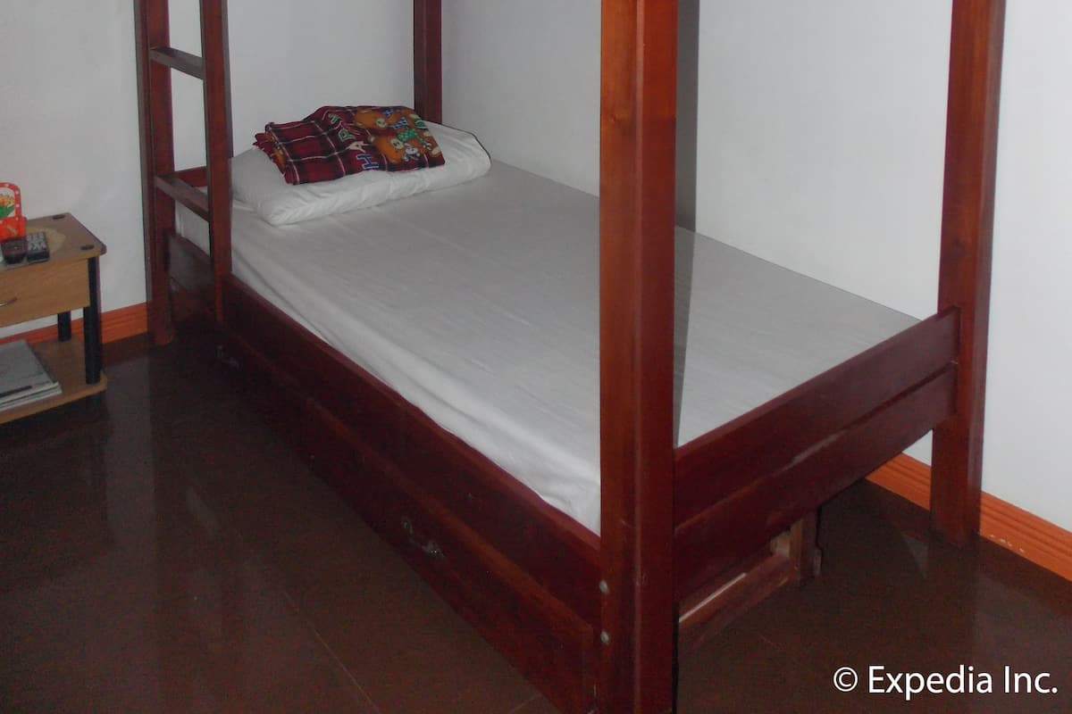 Uma cama beliche com escada, uma mesinha de cabeceira e um aquecedor fixado na parede.