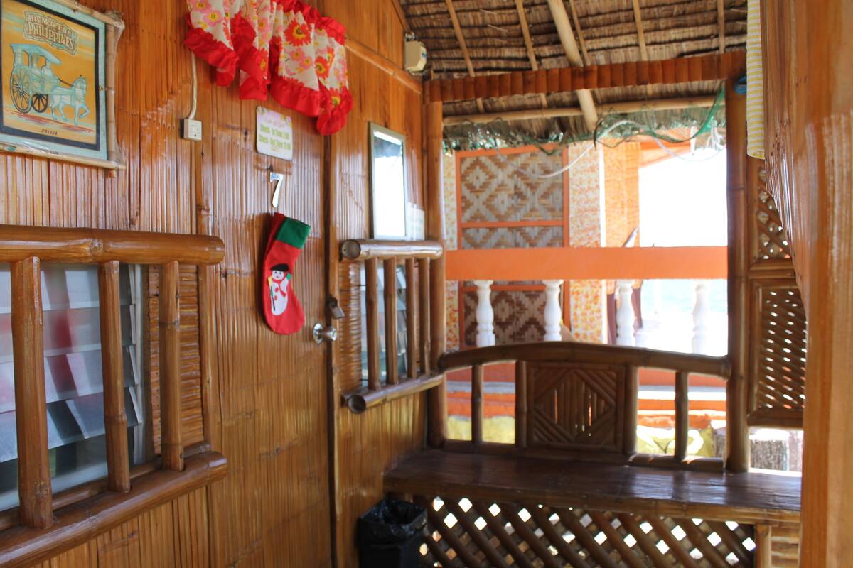 Interior de madeira com um banco, um meião de Natal e uma janela com vista.