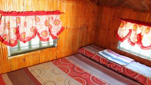 A room with wooden walls, a bed with patterned bedding, and curtains with floral designs. - Maxvir Inn Beach Resort (Oslob)