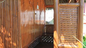 A wooden structure with a bamboo wall, a wooden bench, and a small staircase leading to a higher level. - Maxvir Inn Beach Resort (Oslob)