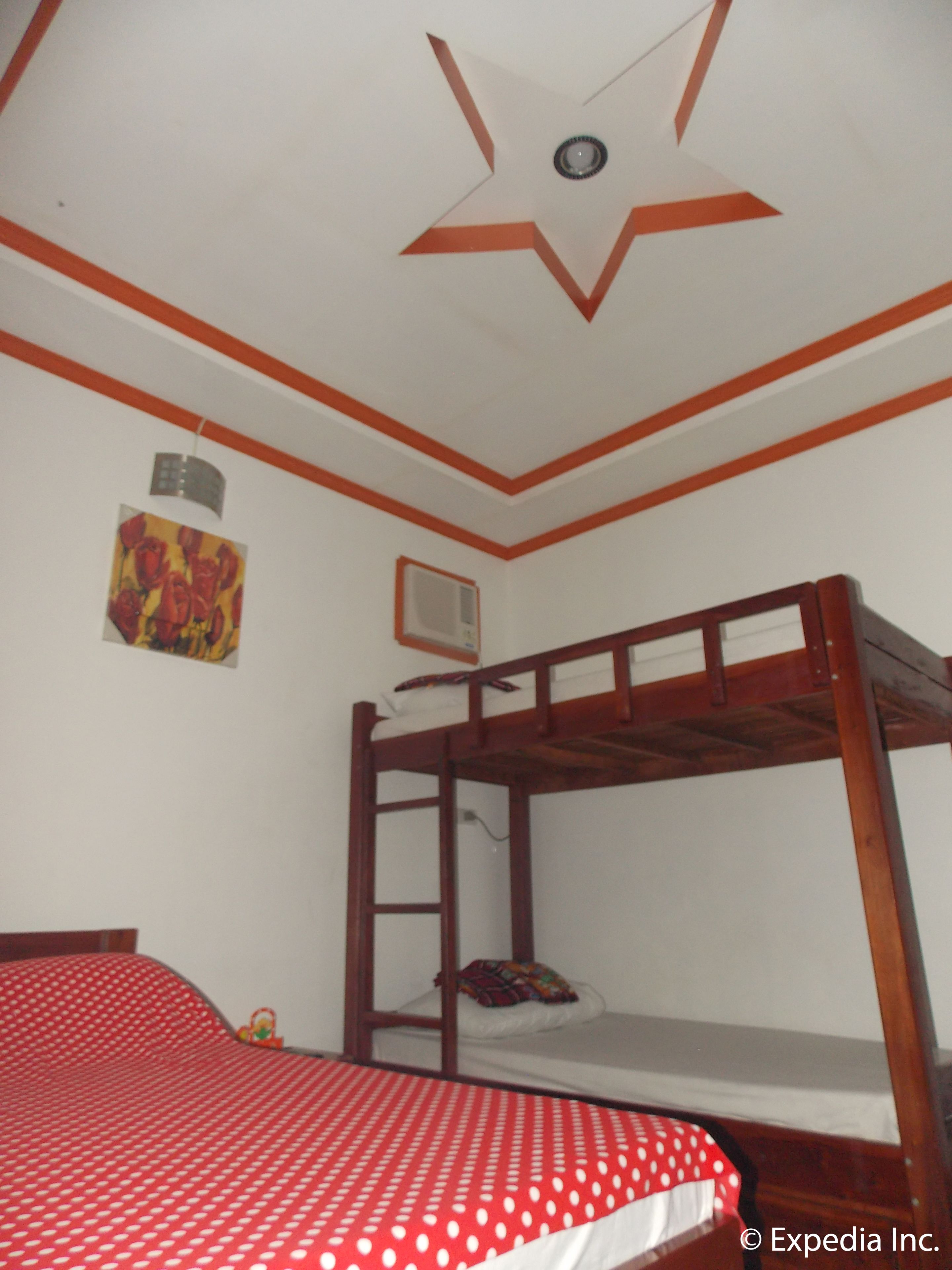 A room with a bunk bed, a ceiling star design, a wall-mounted heater, and a painting.