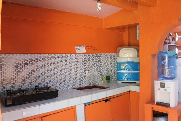 Una cocina con salpicadero de azulejos, dispensador de agua y armarios color naranja.