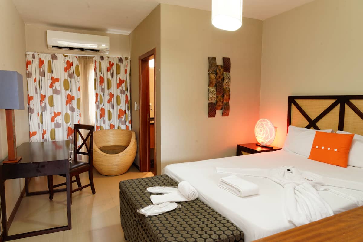 Ein Hotelzimmer mit Bett, Sessel, Tisch und Klimaanlage.