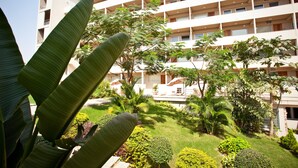 A multi-story hotel with a garden courtyard, including various plants and a pool area.