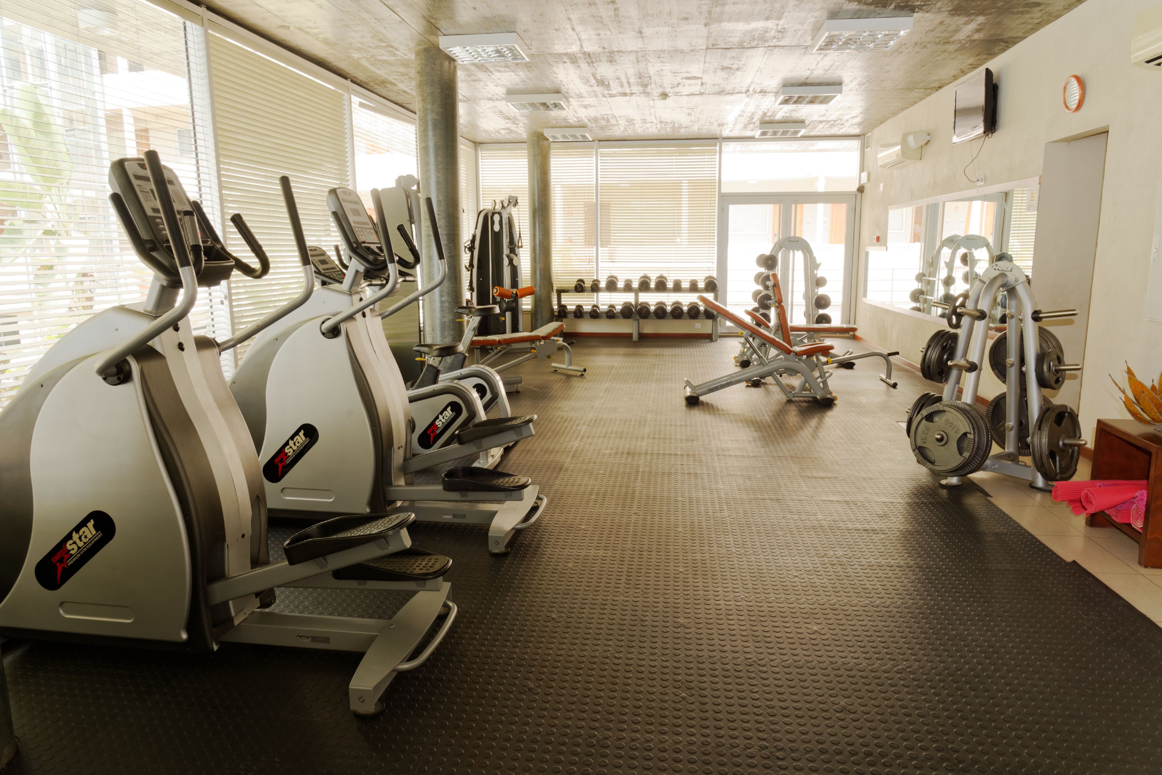 A gym with treadmills, weight machines, and dumbbells.