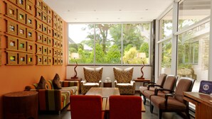 A modern lounge with a large window, multiple chairs, a table, and a wall decorated with framed items.
